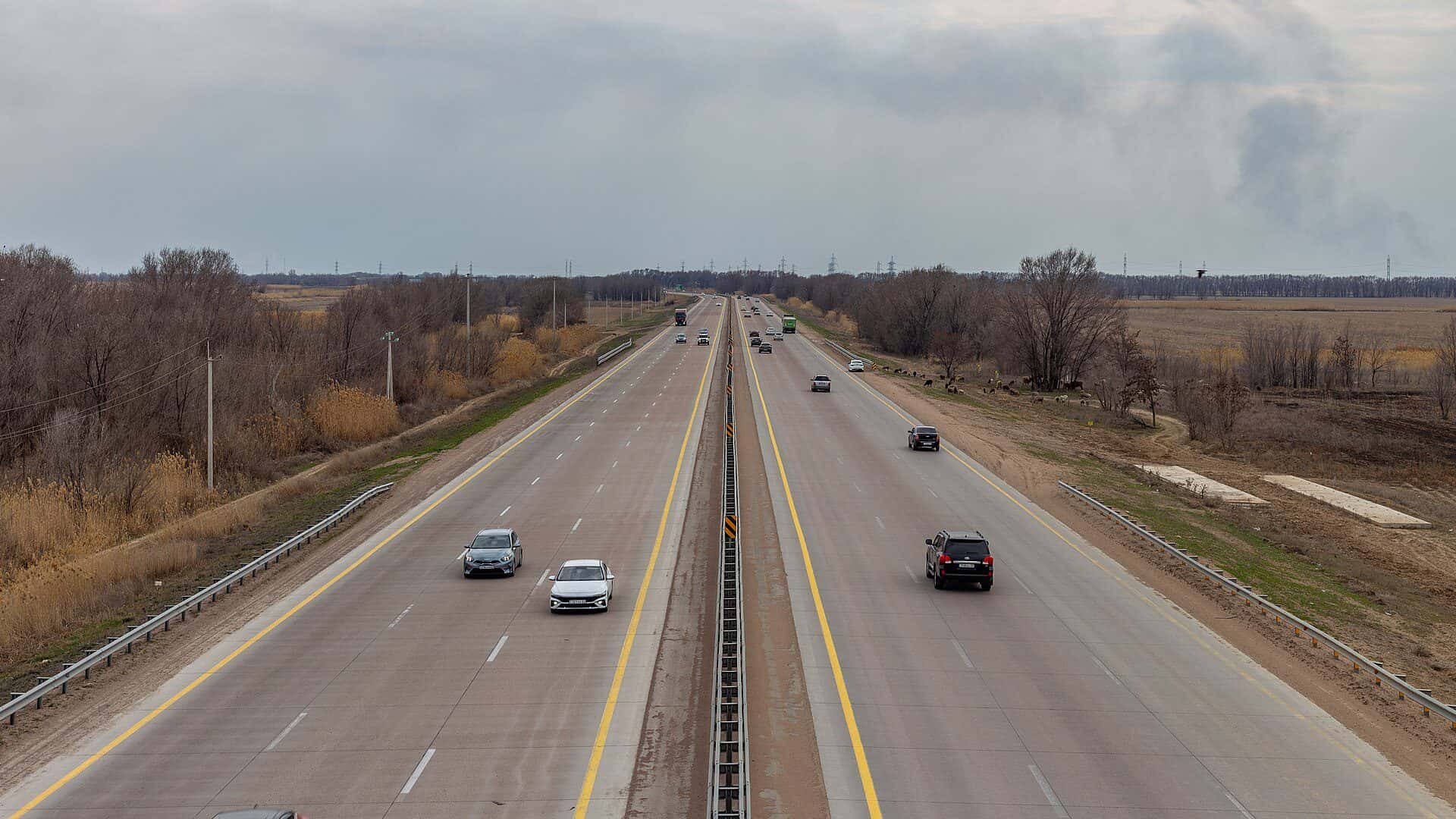 The A-3 highway near Almaty with a median barrier and fields on both sides — intercity travel times and prices