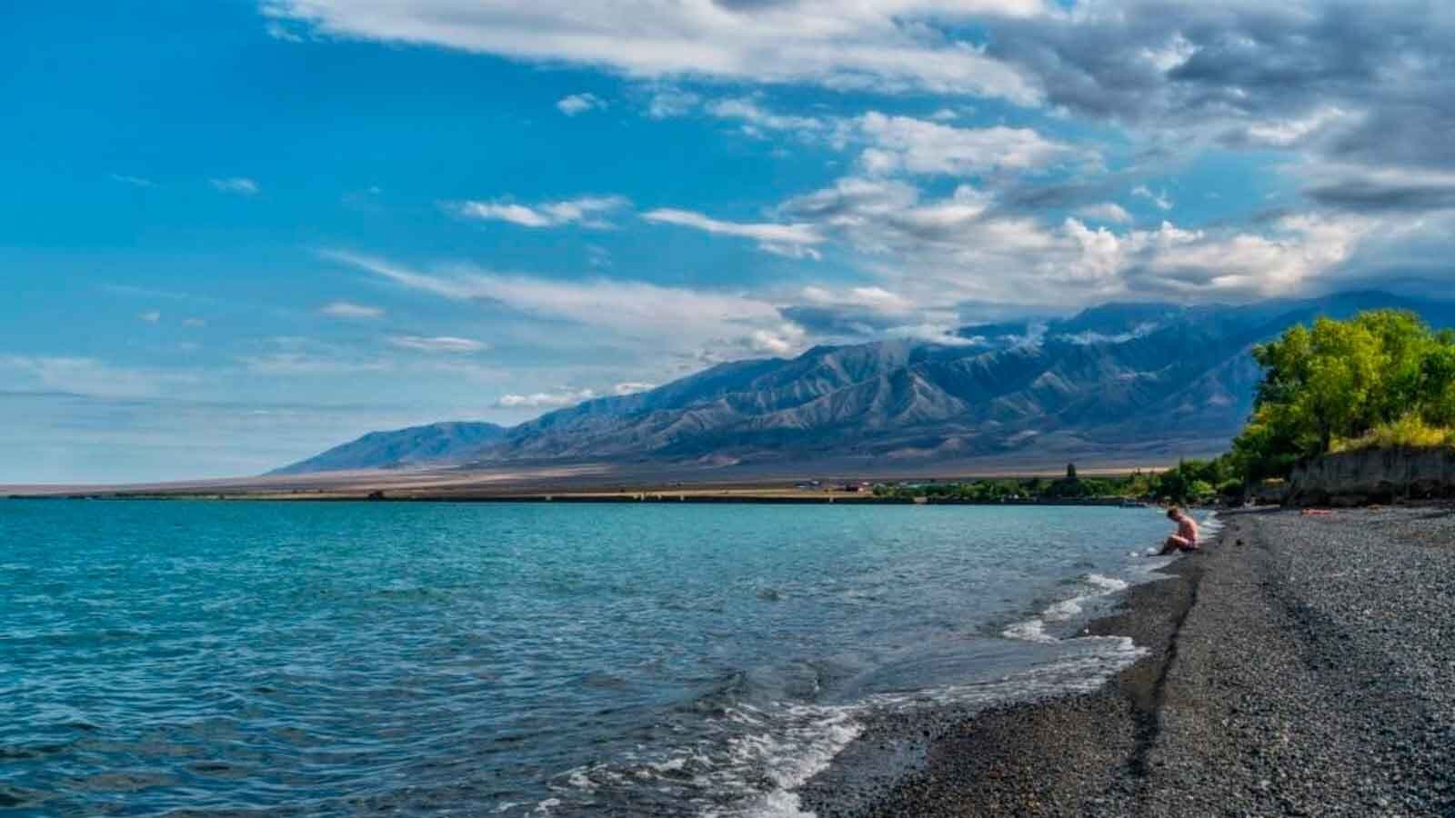 Озеро Алаколь: бирюзовая вода, галечный пляж и горный хребет на горизонте