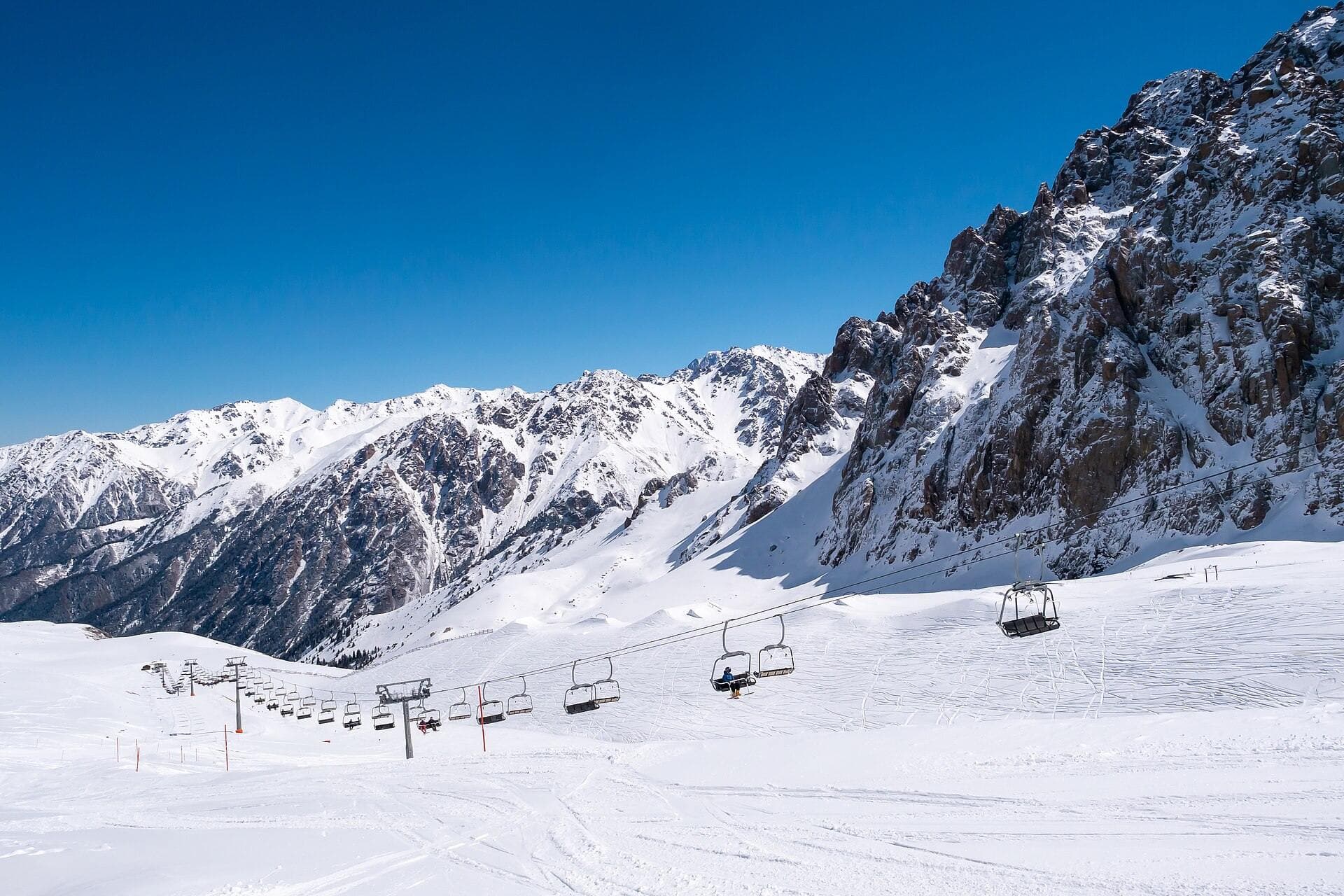 Chairlift and slopes of Shymbulak under the rocky peaks — drop-off at the lower cable car station at Medeu