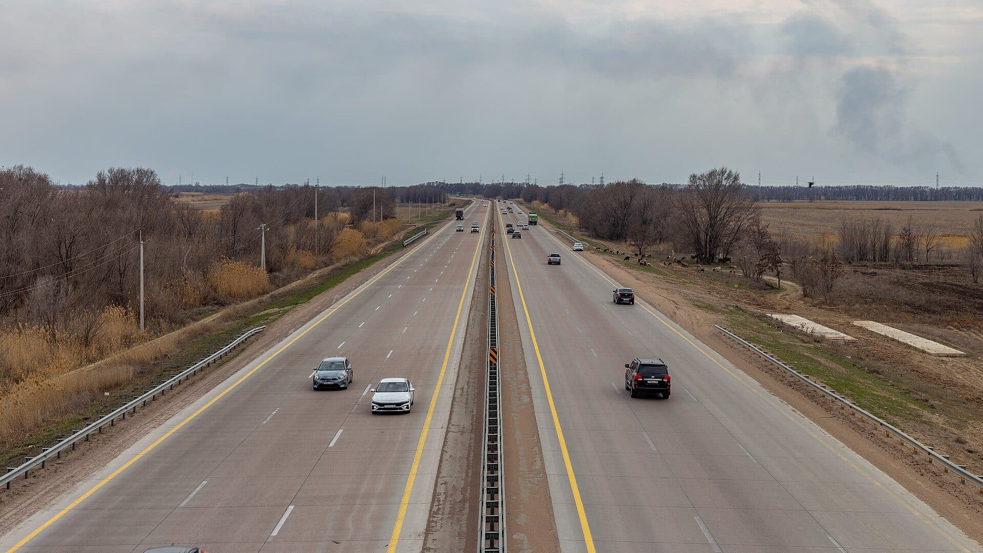 The A-3 highway near Almaty with a median barrier and fields on both sides — intercity travel times and prices